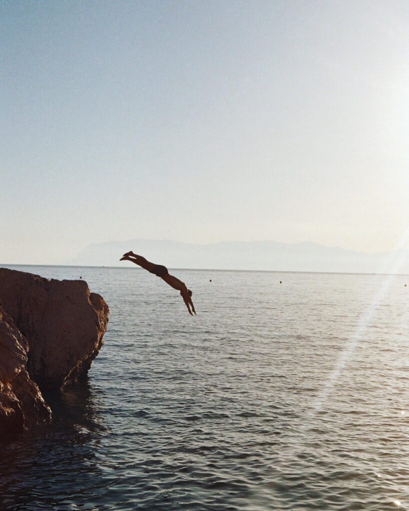 Thrilling dive from rocky cliffs into the deep blue Mediterranean waters.