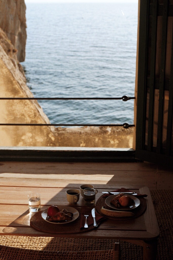 Coastal dining experience with a view of the Mediterranean, rustic setup with a meal near the sea.