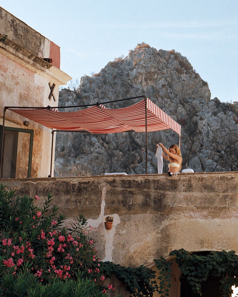 Relaxing rooftop with striped canopy overlooking rocky Mediterranean landscape