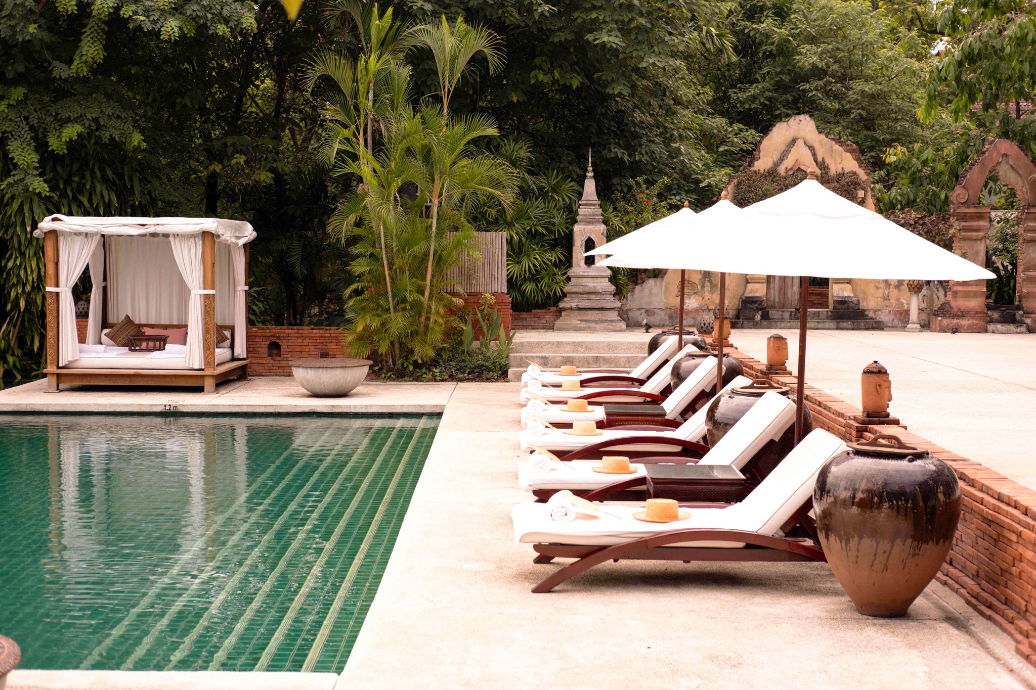 Luxury poolside area with loungers and tropical greenery at Belmond La Résidence Phou Vao