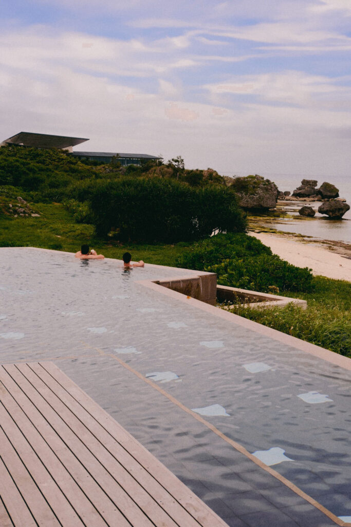 Infinity pool at Hoshinoya Okinawa resort overlooking the ocean with two guests relaxing