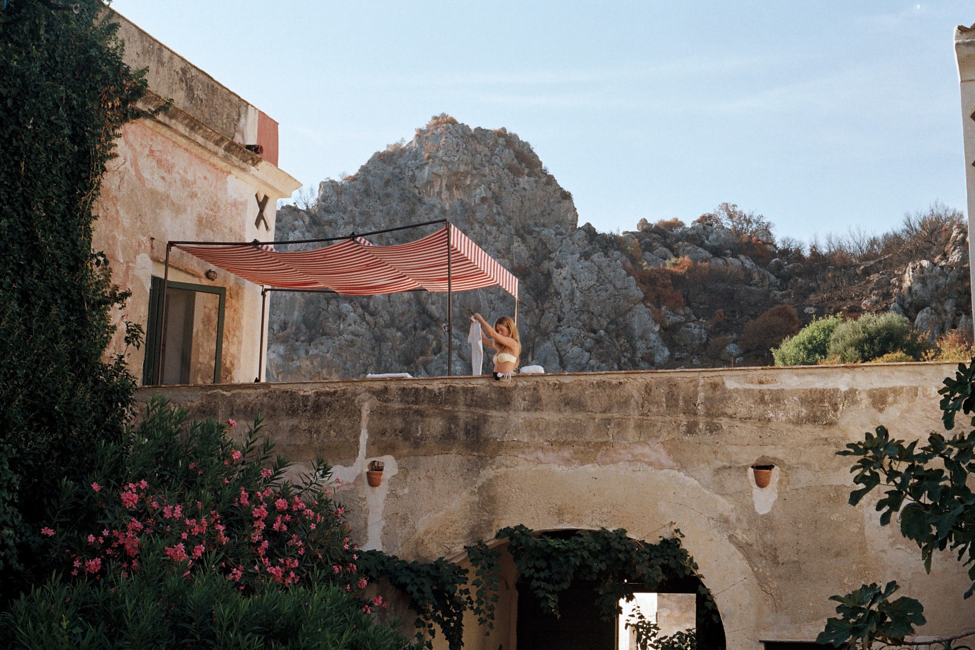 Relaxing rooftop with striped canopy overlooking rocky Mediterranean landscape