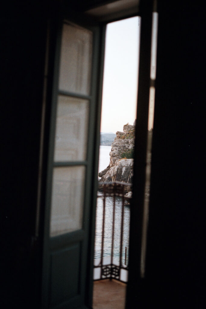 View through a window at Tonnara di Scopello showing the outdoor terrace and coastal scenery