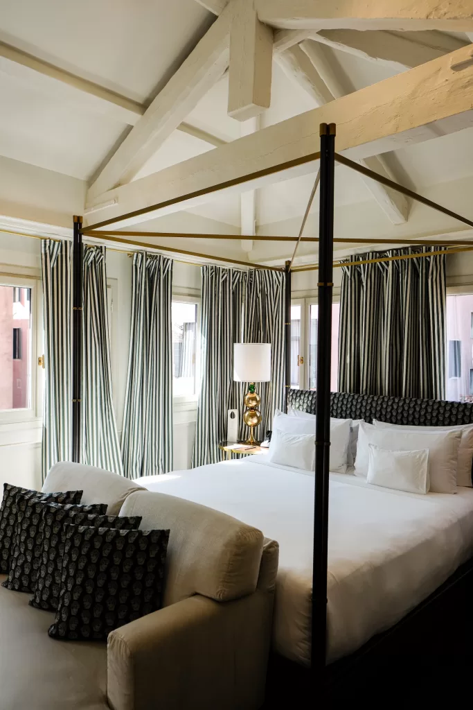 Four poster bed and striped curtains inside a luxury suite at Violino D’Oro hotel in Venice