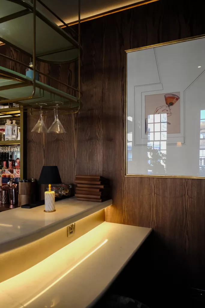 Wood panelled hotel bar with brass shelving and warm lighting at The White Horses