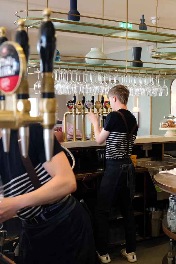 Bartender working behind bar taps at The White Horses coastal hotel