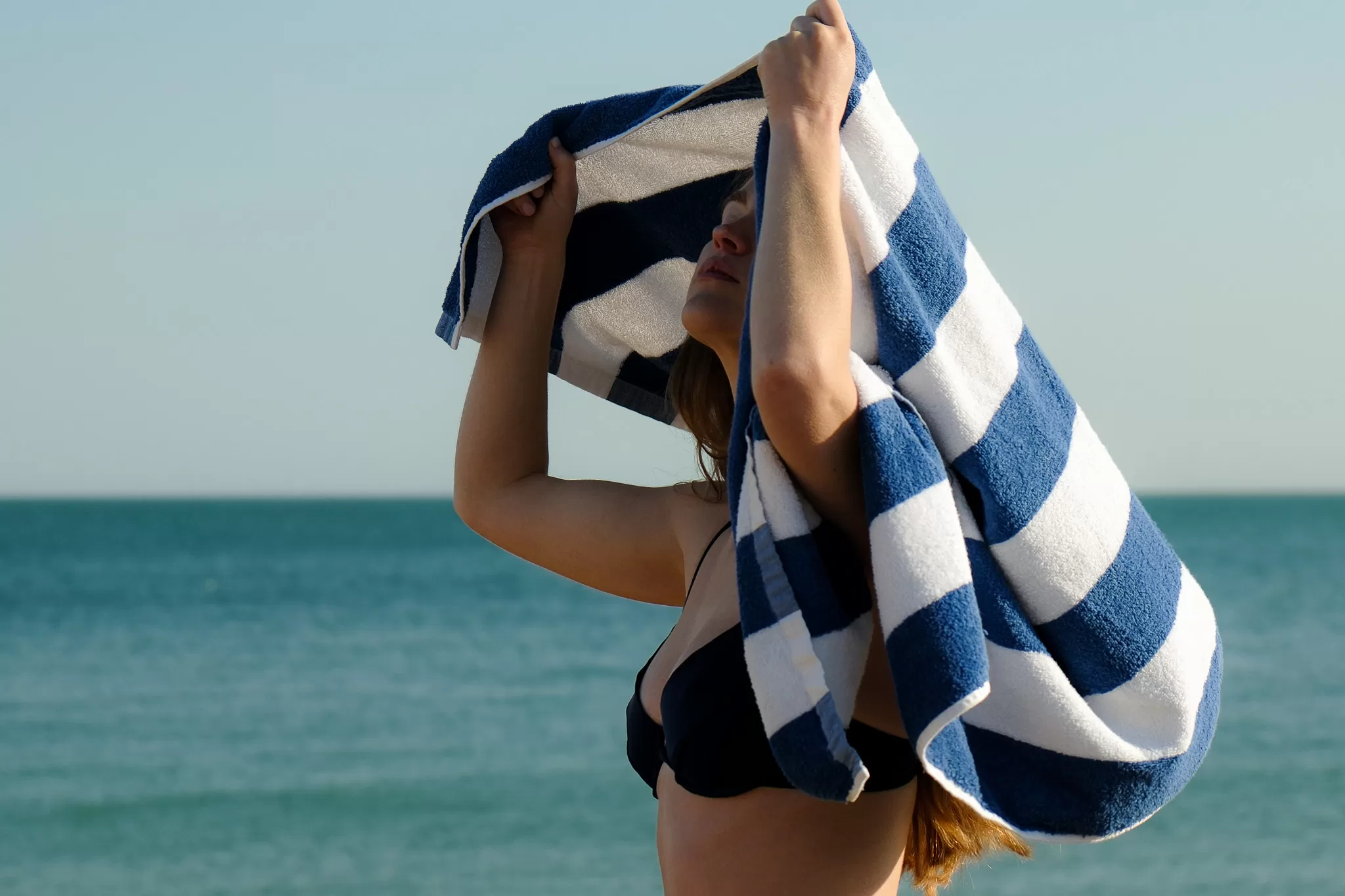 Guest standing by the sea wrapped in striped towel at The White Horses hotel in Rottingdean